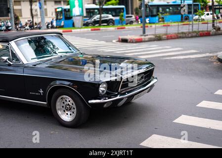 Ho Chi Minh ville, Vietnam - 20 mai 2024 : une Ford Mustang Cabriolet noire classique croisières dans une rue. Banque D'Images