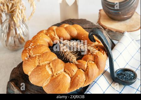 Pain tressé, challah, pain aromatique frais au sel noir. Pain au levain au blé maison. Une miche ronde de pain fraîchement cuit. Banque D'Images