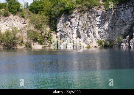 Un magnifique lac turquoise avec des rochers et une verdure luxuriante ajoutant au charme du paysage. Banque D'Images