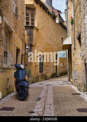 Sarlat, France - 5 mai 2024 : une rue étroite et déserte à Sarlat, en Dordogne. Un scooter stationné apparaît au premier plan. Banque D'Images