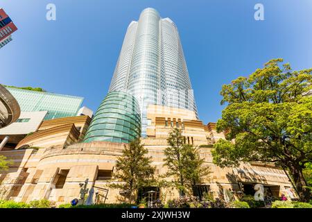 La tour Mori, avec le bâtiment d'entrée du musée d'art Mori en face, surplombant le spectateur dans un ciel bleu clair et un soleil éclatant. Roppongi Hills. Banque D'Images