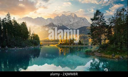 Paysage de lac peint en Allemagne avec des montagnes reflétées dans l'eau turquoise et un beau rayon de soleil du matin illuminant quelques arbres Banque D'Images