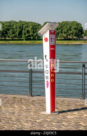 Une boîte d'appel d'urgence rouge et blanche se trouve près du Rhin à Neuwied, en Allemagne. La boîte d'appel a un récepteur téléphonique rouge et signe SOS et DLRG Banque D'Images