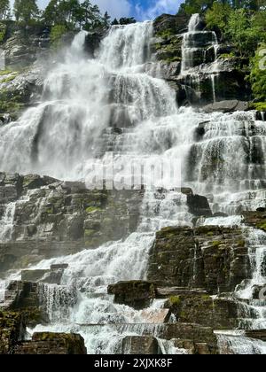 Une cascade est entourée de rochers et d'arbres par une belle journée ensoleillée Banque D'Images