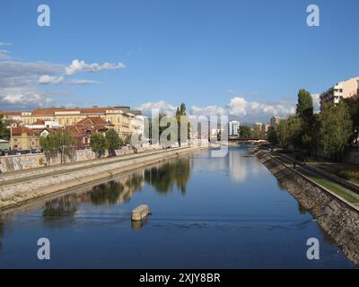 La rivière Nisava traverse la ville de Nis, en Serbie, avec des bâtiments et des arbres bordant ses rives. Banque D'Images