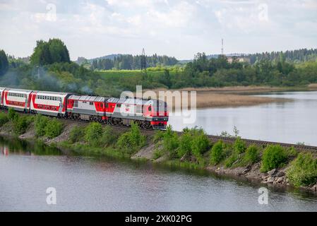 CARÉLIE, RUSSIE - 11 JUIN 2022 : un train de voyageurs à deux étages avec deux locomotives diesel sur le barrage du lac Karmalanyarvi. Carélie, Russie Banque D'Images