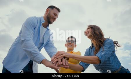 Caucasien famille heureuse femme femme mère homme papa mettant pile main petit garçon fils enfant mains enfant tenant ensemble bras levés ciel aérien montrant Banque D'Images