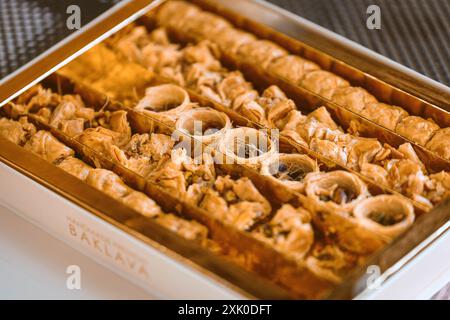 Une vue rapprochée d'une boîte remplie de baklava doré, révélant sa pâte feuilletée en couches et sa garniture sucrée. Banque D'Images