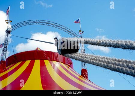 Bridgend, pays de Galles - 7 juillet 2024 : Grande tente de cirque jaune et rouge. Cordes épaisses solides nouées et attachées sur des cliquets métalliques pour assurer la sécurité. Banque D'Images