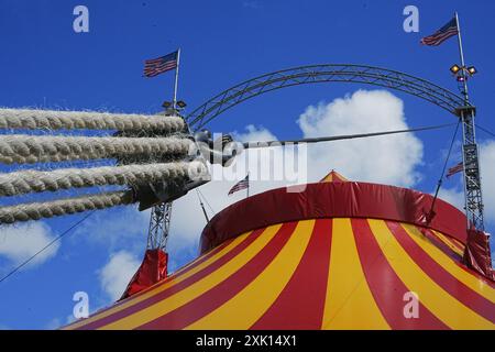 Bridgend, pays de Galles - 7 juillet 2024 : Grande tente de cirque jaune et rouge. Cordes épaisses solides nouées et attachées sur des cliquets métalliques pour assurer la sécurité. Banque D'Images