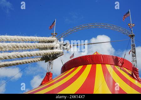 Bridgend, pays de Galles - 7 juillet 2024 : Grande tente de cirque jaune et rouge. Cordes épaisses solides nouées et attachées sur des cliquets métalliques pour assurer la sécurité. Banque D'Images