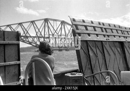 Queensferry, Écosse. 1957 : Une femme à bord du ferry Queensferry passage qui transportait des passagers et des véhicules à travers l'estuaire du Firth of Forth entre North Queensferry et South Queensferry, près d'Édimbourg, en Écosse. Le Forth Railway Bridge est visible au loin. En 1964, les ferries cessent de fonctionner en raison de l'ouverture du pont Forth Road. Banque D'Images