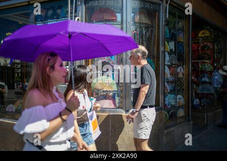 Madrid, Espagne. 20 juillet 2024. Une femme porte un parasol lorsqu'elle passe devant un fan shop dans une rue du centre de Madrid pendant la première vague de chaleur dans la capitale espagnole. (Crédit image : © David Canales/SOPA images via ZUMA Press Wire) USAGE ÉDITORIAL SEULEMENT ! Non destiné à UN USAGE commercial ! Banque D'Images