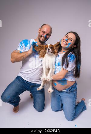Un couple, un homme et une femme enceinte, portant des T-shirts blancs tachés de peinture bleue, attendent un bébé garçon à une soirée de révélation du genre. Ils tiennent un do Banque D'Images