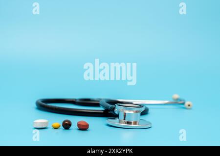 Le stéthoscope d'un médecin est sur une table avec une variété de pilules. Les pilules sont de différentes couleurs et tailles, et le stéthoscope est placé au milieu Banque D'Images