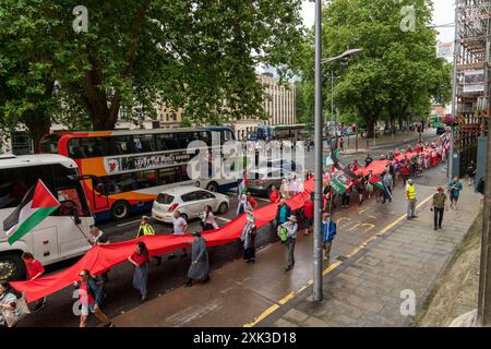 Bristol, Royaume-Uni. 20 juillet 2024. Des centaines de personnes ont transporté un quart de kilomètre de tissu rouge dans les rues du centre de Bristol, pour souligner la guerre contre les habitants de Gaza qui en est maintenant à son neuvième mois. Crédit : Natasha Quarmby/Alamy Live News Banque D'Images