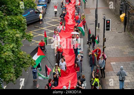 Bristol, Royaume-Uni. 20 juillet 2024. Des centaines de personnes ont transporté un quart de kilomètre de tissu rouge dans les rues du centre de Bristol, pour souligner la guerre contre les habitants de Gaza qui en est maintenant à son neuvième mois. Crédit : Natasha Quarmby/Alamy Live News Banque D'Images