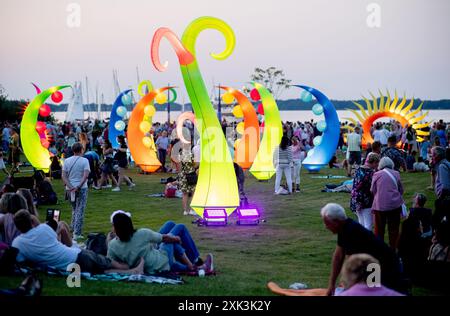 Bad Zwischenahn, Allemagne. 20 juillet 2024. De nombreux visiteurs voient les éléments d'éclairage colorés dans le Kurpark am Zwischenahner Meer pendant la nuit des lumières. Dans le cadre de la nuit des lumières, les jardins du spa de Bad Zwischenahn ont été transformés en une mer de couleurs. Crédit : Hauke-Christian Dittrich/dpa/Alamy Live News Banque D'Images