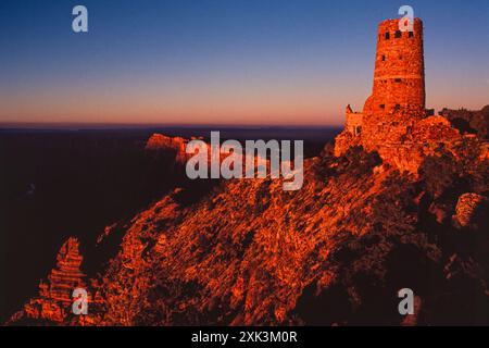 Une vue au coucher du soleil de la tour de guet Desert View, un bâtiment en pierre de 70 pieds de haut, et la zone la plus développée à l'est sur le plateau sud du Grand Canyon dans le parc national du Grand Canyon en Arizona, aux États-Unis. Aussi connue sous le nom de tour de guet indienne à Desert View, elle a été conçue en 1932 par l'architecte Mary Colter. Banque D'Images