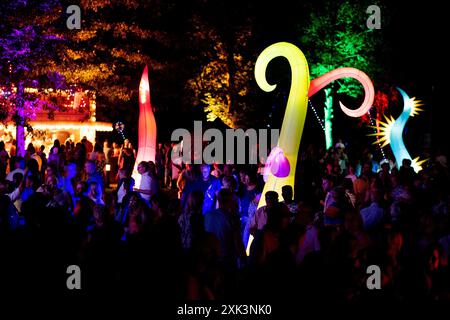 Bad Zwischenahn, Allemagne. 20 juillet 2024. De nombreux visiteurs voient les éléments d'éclairage colorés dans le Kurpark am Zwischenahner Meer pendant la nuit des lumières. Dans le cadre de la nuit des lumières, les jardins du spa de Bad Zwischenahn ont été transformés en une mer de couleurs. Crédit : Hauke-Christian Dittrich/dpa/Alamy Live News Banque D'Images