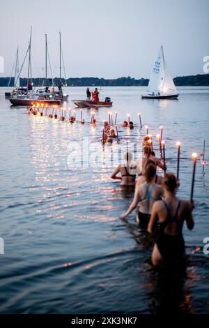 Bad Zwischenahn, Allemagne. 20 juillet 2024. De nombreux nageurs DLRG entrent dans le Zwischenahner Meer avec des torches brûlantes pendant la nuit des lumières. Dans le cadre de la nuit des lumières, les jardins du spa de Bad Zwischenahn se transforment en une mer de couleurs. Crédit : Hauke-Christian Dittrich/dpa/Alamy Live News Banque D'Images