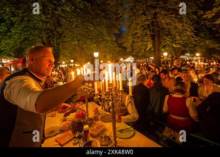 Kocherlball am Chinesischen Turm, Biertrinken BEI Kerzenschein um 4:45 Uhr, München, 21. Juillet 2024 Deutschland, München, 21. Juillet 2024, Biertrinken BEI Kerzenschein um 4:45 Uhr, Kocherlball am Chinesischen Turm, Thomas Trabandt ist extra aus Hamburg gekommen, um mit Freunden hier zu feiern, zündet selbst mitgebrachten Kerzenleuchter an, Englischer Garten, Besucher feiern Früh morgens, sitzen schon teilweise ab 4 Uhr Früh im Biergarten, trinken ein Bier, essen eine Brotzeit, tragen Tracht, tradition entstand im 19. Jahrhundert, als HausPersonal, Dienstboten und KöchInnen in den frühen Morgenstu Banque D'Images