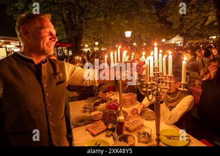 Kocherlball am Chinesischen Turm, Biertrinken BEI Kerzenschein um 4:45 Uhr, München, 21. Juillet 2024 Deutschland, München, 21. Juillet 2024, Biertrinken BEI Kerzenschein um 4:45 Uhr, Kocherlball am Chinesischen Turm, Thomas Trabandt ist extra aus Hamburg gekommen, um mit Freunden hier zu feiern, zündet selbst mitgebrachten Kerzenleuchter an, Englischer Garten, Besucher feiern Früh morgens, sitzen schon teilweise ab 4 Uhr Früh im Biergarten, trinken ein Bier, essen eine Brotzeit, tragen Tracht, tradition entstand im 19. Jahrhundert, als HausPersonal, Dienstboten und KöchInnen in den frühen Morgenstu Banque D'Images