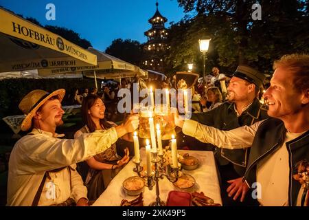 Kocherlball am Chinesischen Turm, Biertrinken BEI Kerzenschein um 4:50 Uhr, München, 21. Juillet 2024 Deutschland, München, 21. Juillet 2024, Biertrinken BEI Kerzenschein um 4:50 Uhr, Kocherlball am Chinesischen Turm, Englischer Garten, Freunde sind extra aus Wien gekommen, um hier mitzufeiern, Früh morgens, halb in der Nacht, trinken ein Bier, essen eine Brotzeit, tragen Tracht, tradition entstand im 19. Jahrhundert, als HausPersonal, Dienstboten und KöchInnen in den frühen Morgenstunden vor Dienstbeginn gefeiert und getanzt haben, tradition wurde ab 1989 wiederbelebt, traditionell am 3. Sonntag im Banque D'Images