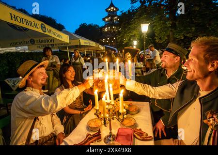 Kocherlball am Chinesischen Turm, Biertrinken BEI Kerzenschein um 4:50 Uhr, München, 21. Juillet 2024 Deutschland, München, 21. Juillet 2024, Biertrinken BEI Kerzenschein um 4:50 Uhr, Kocherlball am Chinesischen Turm, Englischer Garten, diese Freunde sind extra aus Wien gekommen, um hier mitzufeiern, Früh morgens, halb in der Nacht, trinken ein Bier, essen eine Brotzeit, tragen Tracht, tradition entstand im 19. Jahrhundert, als HausPersonal, Dienstboten und KöchInnen in den frühen Morgenstunden vor Dienstbeginn gefeiert und getanzt haben, tradition wurde ab 1989 wiederbelebt, traditionell am 3. Sonn Banque D'Images