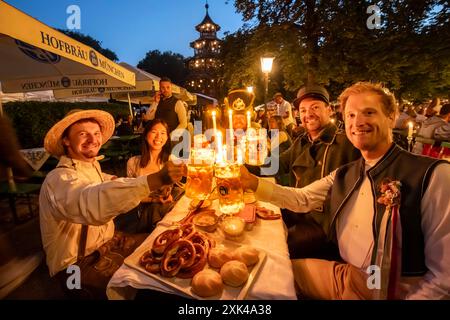 Kocherlball am Chinesischen Turm, Biertrinken BEI Kerzenschein um 4:50 Uhr, München, 21. Juillet 2024 Deutschland, München, 21. Juillet 2024, Biertrinken BEI Kerzenschein um 4:50 Uhr, Kocherlball am Chinesischen Turm, Englischer Garten, diese Freunde sind extra aus Wien gekommen, um hier mitzufeiern, Früh morgens, halb in der Nacht, trinken ein Bier, essen eine Brotzeit, tragen Tracht, tradition entstand im 19. Jahrhundert, als HausPersonal, Dienstboten und KöchInnen in den frühen Morgenstunden vor Dienstbeginn gefeiert und getanzt haben, tradition wurde ab 1989 wiederbelebt, traditionell am 3. Sonn Banque D'Images