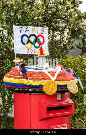 Topper de boîte aux lettres tricoté coloré célébrant les Jeux Olympiques de Paris 2024 avec médailles crochetées, athlètes, flamme et anneaux olympiques, Weymouth, Dorset Banque D'Images