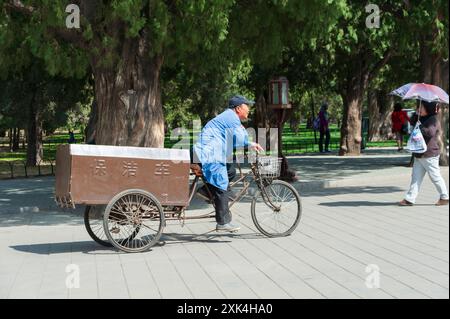 Chine, Pékin, 13 avril 2012. Homme chinois chevauchant un tricycle de cargaison pour la collecte des ordures dans une rue de la ville Banque D'Images