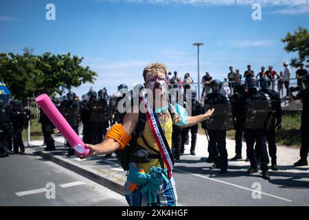 La Rochelle, France. 20 juillet 2024, la Rochelle, France : un manifestant contre les méga bassins industriels se tient devant la police, les bras tendus. Son visage est peint de maquillage de clown et il porte une ceinture de député lisant le nom du ministre de l'intérieur français, Gérald Darmanin. Crédit : Jay Kogler/Alamy Live News crédit : Jay Kogler/Alamy Live News Banque D'Images