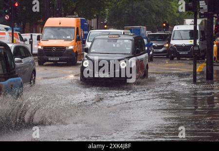 Londres, Royaume-Uni. 9 juillet 2024. Un taxi jaillit sur une Euston Road bordée d'eau alors que de fortes pluies inondent la capitale. Crédit : Vuk Valcic/Alamy Banque D'Images