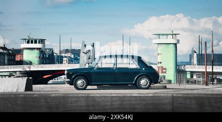 Morris 1300 bleu foncé garé sur un quai. Vue de profil de côté du petit salon familial britannique des années 1960 devant le pont Langebro. Banque D'Images