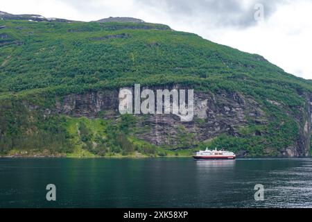 Geiranger Fjord Norvège 5 juillet 2024, Un bateau de croisière navigue à travers un fjord norvégien pittoresque, entouré de falaises imposantes et d'une végétation luxuriante. Banque D'Images