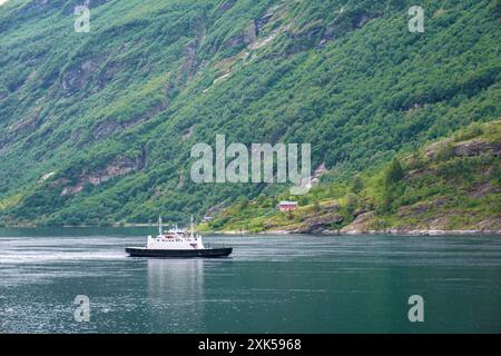 Geiranger Fjord Norvège 5 juillet 2024, Un ferry traverse un fjord norvégien serein, entouré de montagnes verdoyantes et d'eaux bleues limpides. Banque D'Images