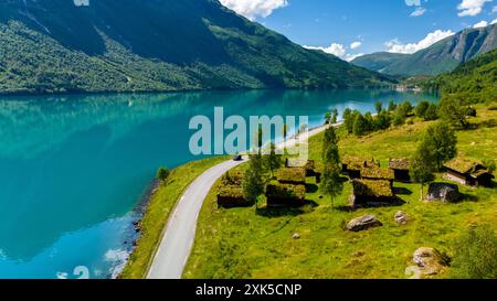 Une route pittoresque traverse une vallée verdoyante, menant à un fjord turquoise niché entre des montagnes imposantes. Lovatnet lac Lodal vallée Norvège Banque D'Images