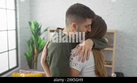 Un couple aimant embrasse dans un intérieur de maison confortable, exprimant l'affection et la convivialité. Banque D'Images