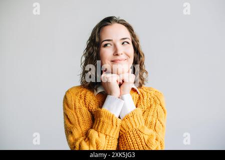 Femme souriante avec les mains sur Chin. Une jeune femme joyeuse avec un sourire éclatant, reposant son menton sur ses mains. Parfait pour les thèmes du bonheur Banque D'Images