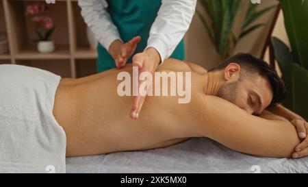 Patient masculin recevant un massage thérapeutique dans un centre de bien-être par un masseur professionnel sur une table de traitement Banque D'Images