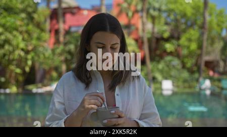 Une jeune femme profitant d'une tasse de café au bord d'une piscine de Resort dans la région tropicale de bali, indonésie. Banque D'Images