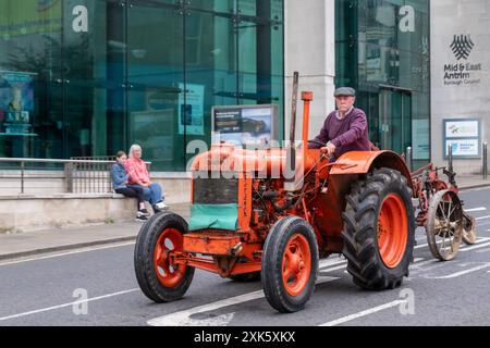 Ballymena, Irlande du Nord - 19 juillet 2024 : Vintage Tractor Rally, magnifique tracteur orange Fordson passant devant l'hôtel de ville sur Bridge Street. Banque D'Images