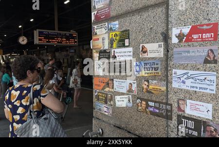 TEL AVIV, ISRAËL- 21 JUILLET : les navetteurs se tiennent à côté d'un mur avec des autocollants commémoratifs commémorant les soldats de Tsahal tués dans la guerre israélienne contre Gaza et ter­ror vic­tims après Octo­ber 7, dans la gare de Hashalom, au milieu des batailles continues entre Israël et le groupe militant Hamas à Gaza le 21 juillet 2024 à tel Aviv. Israël. Banque D'Images