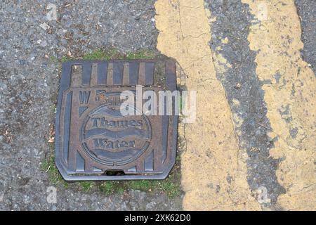 Eton, Royaume-Uni. 21 juillet 2024. Un couvercle de drain d'eau de la Tamise à Eton, Windsor, Berkshire. Les poursuites engagées contre Thames Water par l'Agence de l'environnement pour des incidents de pollution ont abouti à des amendes de 35 millions de livres sterling entre 2017 et 2023. Le projet de loi sur l’eau (mesures spéciales) a été annoncé dans le discours du roi cette semaine. L'objectif du projet de loi, s'il est adopté, serait de renforcer les régulateurs de l'eau en donnant de nouveaux pouvoirs pour interdire le paiement de primes aux dirigeants des compagnies d'eau en cas de violation des normes environnementales. Les dirigeants des compagnies d'eau pourraient également faire l'objet de sanctions pénales. Crédit : Maureen McLean/Alamy Banque D'Images