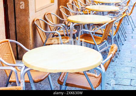 Rangée de tables vides avec chaises dans la rue. Les chaises sont en bois et en métal. Les tables sont rondes et ont un dessus blanc. Les chaises sont arrang Banque D'Images