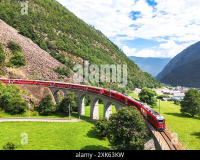 Vue aérienne d'un train Bernina Express traversant le viaduc en spirale Brusio du chemin de fer rhétique, canton des Grisons, Suisse Banque D'Images