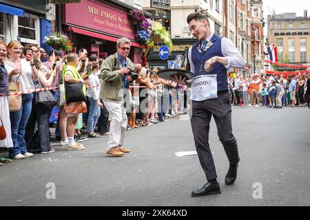 Londres, 21 juillet 2024. Participants sur la ligne d'arrivée. Des dizaines de participants à la course des serveurs de Soho courent le long d'un itinéraire fixe à Soho avec un plateau, des verres et du champagne, puis célèbrent la course et célèbrent dans les rues de Soho. L'événement traditionnel amusant voit le personnel de service de nombreux bars, pubs et restaurants de la région concourir chaque année. Crédit : Imageplotter/Alamy Live News Banque D'Images