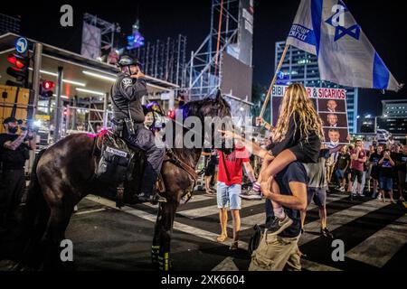 Tel Aviv, Israël. 20 juillet 2024. Un manifestant avec un enfant sur ses épaules pointe vers un policier monté à cheval lors d'un rassemblement de protestation à tel Aviv, le samedi 20 juillet 2024. Des manifestants antigouvernementaux se sont rassemblés dans des villes à travers Israël samedi soir, appelant le premier ministre Benjamin Netanyahu à ne pas partir pour une visite prévue à Washington le lendemain tant qu’il n’aura pas signé un accord avec le Hamas pour faciliter le retour de l’otage de Gaza. Crédit : Eyal Warshavsky/Alamy Live News Banque D'Images