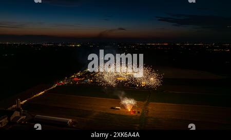 Feux d'artifice dorés création d'Un nuage étincelant dense dans le ciel nocturne, illuminant Un rassemblement avec des tentes et les lumières lointaines de la ville, avec Un horizon crépusculaire ajoutant à la scène festive. Banque D'Images